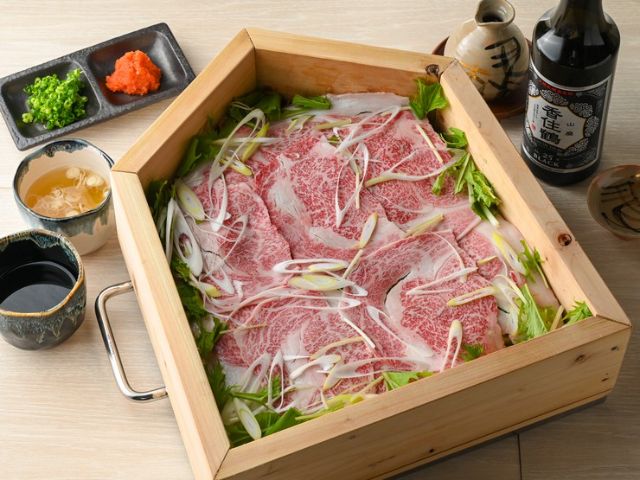 Savoring the 'Specialty Kangien Seiro-mushi,' served in a specially ordered steamer shaped like shogi pieces.